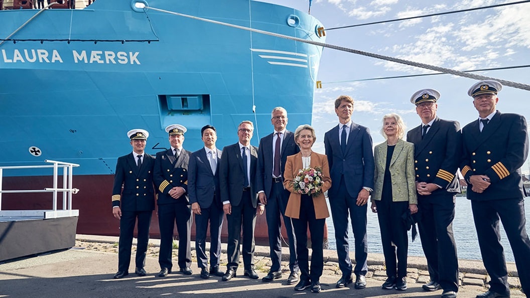 Officials and crew stand in front of the blue hull of the Laura Mærsk at its naming ceremony.