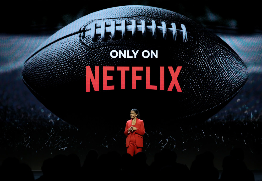 Netflix Upfront stage: a presenter stands below a football-shaped Only on Netflix graphic.